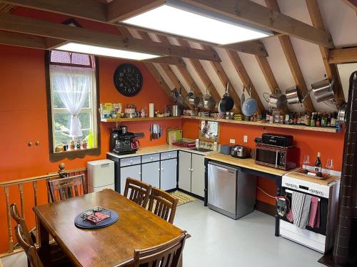 uma cozinha com paredes cor de laranja, uma mesa de madeira e uma sala de jantar em Cubby House Stay Kaikoura em Kaikoura