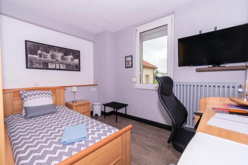 a bedroom with a bed and a desk and a television at Private & Comfortable Apartments in Puttelange-aux-Lacs