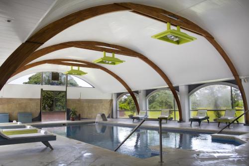an indoor swimming pool with arched ceilings and a large swimming pool at Estancia Turística Don Joaquín in Scavino