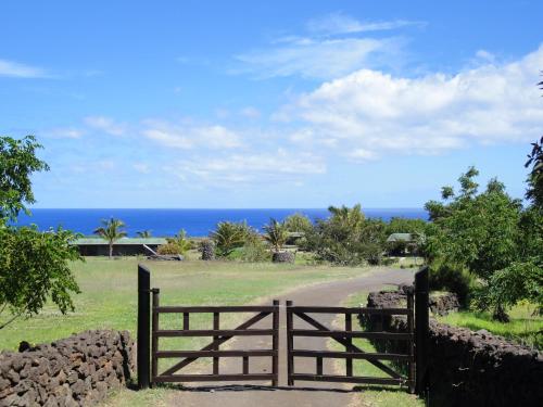 a gate to a field with the ocean in the background at Heva Eco Lodge in Hanga Roa