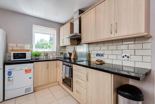 a kitchen with wooden cabinets and a black counter top at The Oxford Abode - 3-Bedroom House - large garden & free parking in Oxford