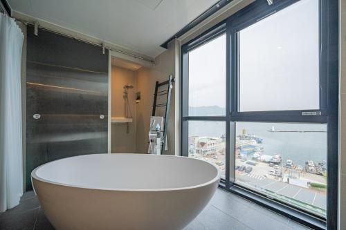 La salle de bains est pourvue d'une grande baignoire et d'une grande fenêtre. dans l'établissement Louis Boutique Hotel, à Changwon