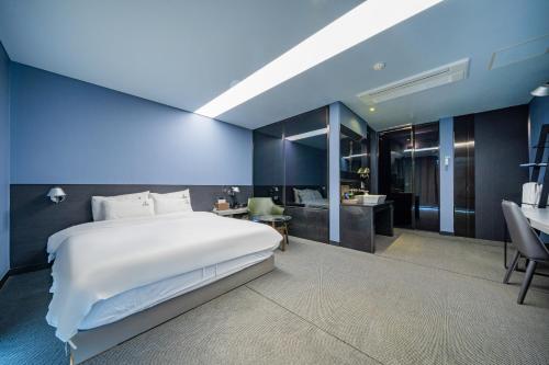 a bedroom with a large white bed and a bathroom at Louis Boutique Hotel in Changwon