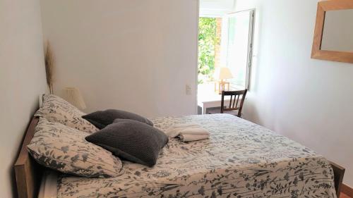 ein Schlafzimmer mit einem Bett mit Kissen und einem Fenster in der Unterkunft Aux Chambres du Chadoux de Chateaubourg (ChaChaCha) in Châteaubourg