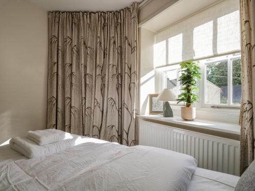 a bedroom with a bed with a curtain and a window at Endgill Cottage in Ulverston