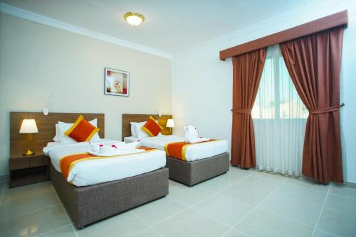 una camera d'albergo con due letti e una finestra di La Villa Inn Hotel Apartments a Doha