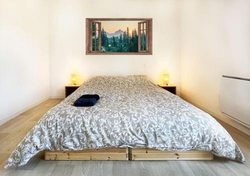 een bed in een slaapkamer met een foto aan de muur bij Charmant T3 en plein centre du Bousquet-d'Orb in Le Bousquet-dʼOrb