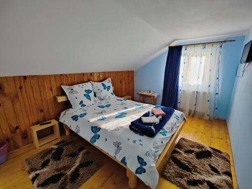 a bedroom with a bed with a blue and white comforter at Casa Poiana Teiului in Poiana Teiului
