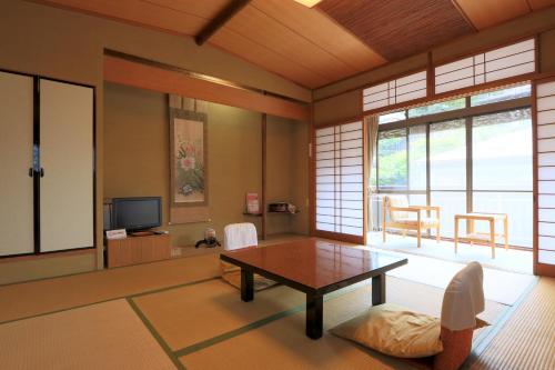 a living room with a table and a tv at Kamiobo in Kobe