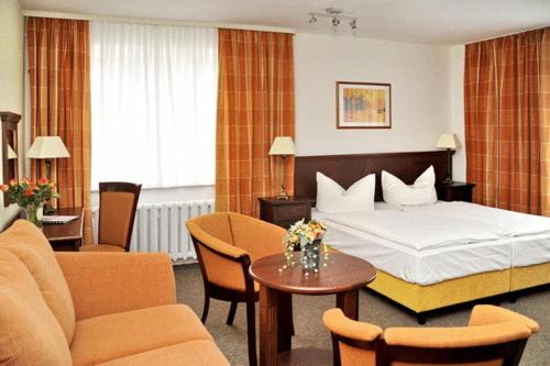 a hotel room with a bed and a table and chairs at Hotel Störtebeker in Graal-Müritz