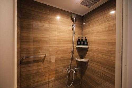 y baño con ducha y paredes de madera. en Colorit GOTO ISLANDS, en Goto