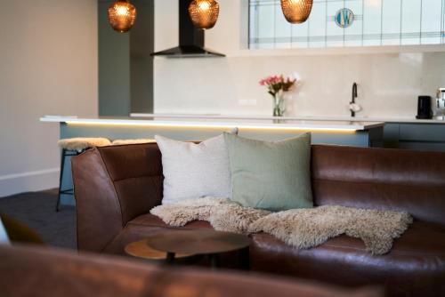 a brown leather couch with pillows in a living room at Laneway Apartments - The Residence in Napier