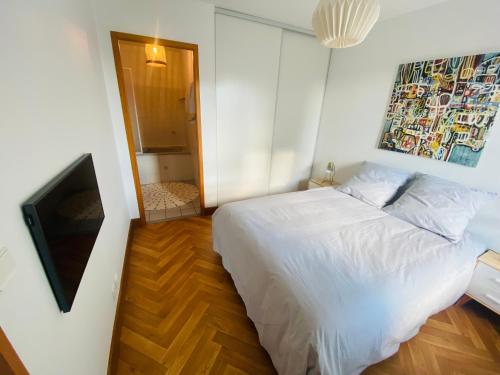 um quarto com uma cama branca e uma televisão em Appartement Saint Claude - Centre Port em La Rochelle