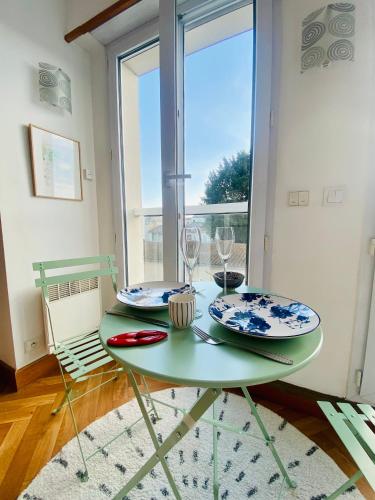 una mesa verde con dos platos y vasos. en Appartement Saint Claude - Centre Port, en La Rochelle