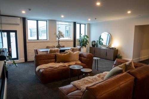 sala de estar con muebles de cuero marrón y espejo en Laneway Apartments, en Napier