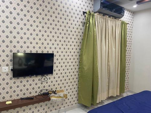 a bedroom with a tv on a wall at Grey Orchard Homestay - A Family Place in Lahore