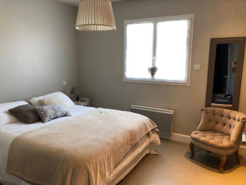 a bedroom with a bed and a chair and a window at Charmante maison à proximité de Bordeaux in Gradignan