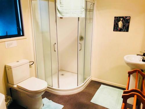 a bathroom with a shower and a toilet and a sink at Paradise Valley River Lodge in Rotorua
