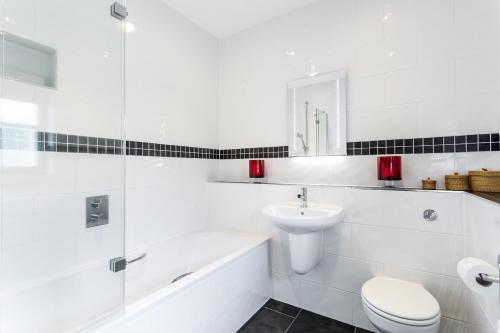 a white bathroom with a toilet and a sink at Holly Cottage in Honiton