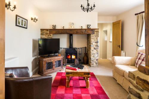 a living room with a couch and a fireplace at Holly Cottage in Honiton
