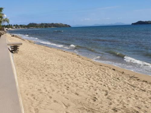 a sandy beach with a bench and the ocean at Beach Loft in Nosy Be