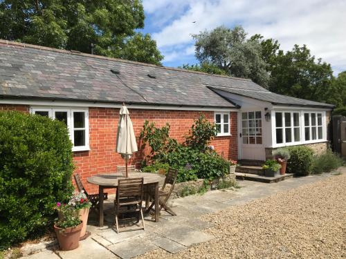 a red brick house with a table and an umbrella at Norburton Hall Cottages in Bridport