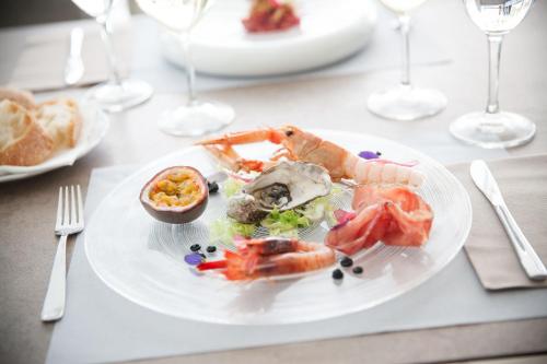 a plate of seafood on a table with wine glasses at Hotel Torino Wellness & Spa in Diano Marina