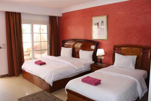 two beds in a room with red walls at Herrmes Hospitality in Sharm El Sheikh