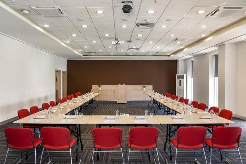 a large conference room with a long table and red chairs at ibis Adana in Adana
