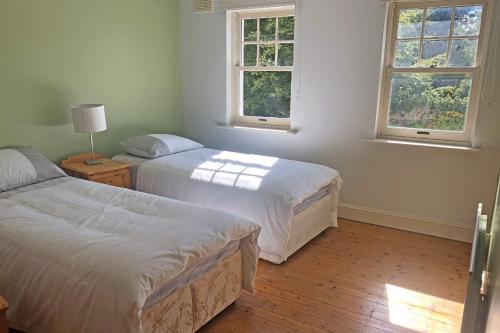 2 Betten in einem Zimmer mit 2 Fenstern in der Unterkunft Courtyard Holiday Cottage No 8 in Bettystown