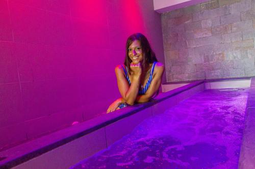 a woman sitting in a hot tub with purple lights at MARINO WELLNESS in Ali Terme