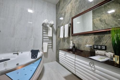 W łazience znajduje się wanna, umywalka i lustro. w obiekcie East Star Hotel w Samarkandzie