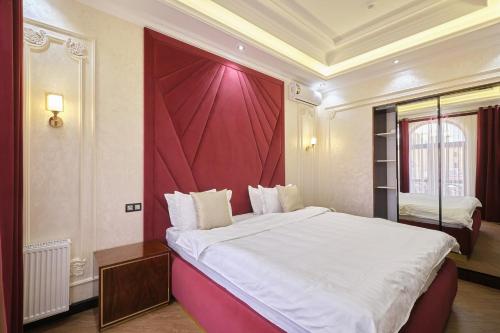 a bedroom with a large bed with a red wall at East Star Hotel in Samarkand