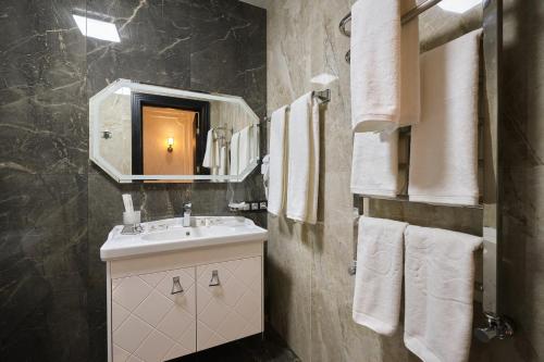 a bathroom with a sink and a mirror and towels at East Star Hotel in Samarkand