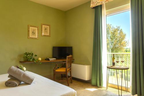 a bedroom with a bed and a desk and a window at Fattoria di Magliano Winery in Magliano in Toscana