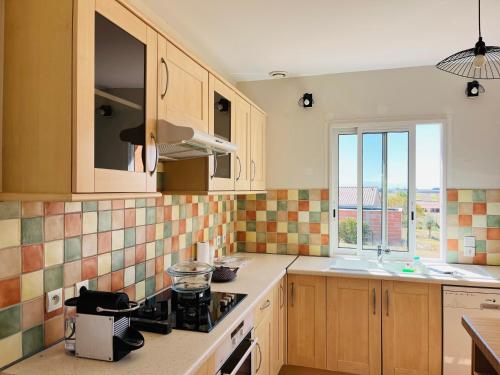 a kitchen with a stove and a sink and a window at Jolie villa au cœur du Lauragais in Lanta