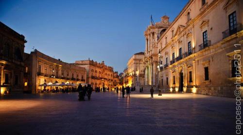 a city street at night with people walking around at Sweet Home & Apartments in Fontane Bianche