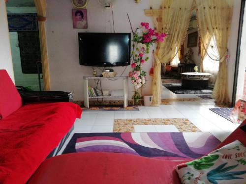 a living room with a red couch and a flat screen tv at Love homestay CT in Kangar