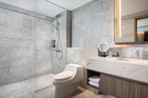 Oakwood Suites Kuningan Jakarta في جاكرتا: حمام مع دش ومرحاض ومغسلة