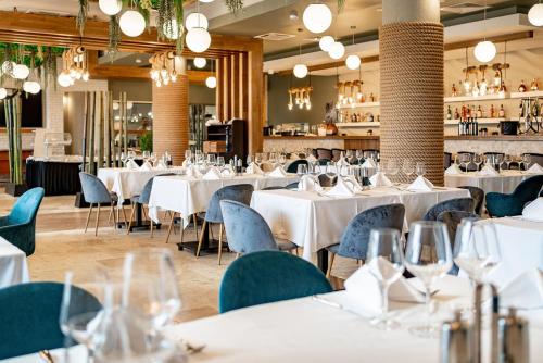 une salle à manger avec des tables blanches et des chaises bleues dans l'établissement Razelm Luxury Resort, à Jurilovca