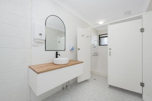 a white bathroom with a sink and a mirror at Seaside Lodge Townsville in Townsville