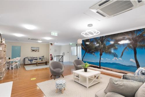 a living room with a palm tree mural at Seaside Lodge Hostel Townsville- right next to coles, 2 mins walk to strand & CBD- Passport required in Townsville