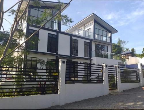 a large white house with a fence in front of it at Check out this beautiful 5 bed villa with pool!! in Baclayon