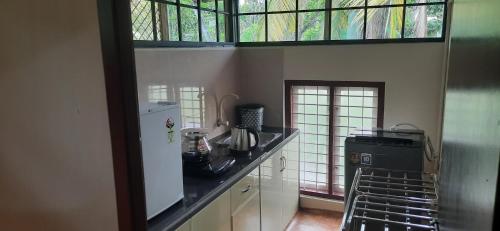 a kitchen with a white refrigerator and a window at NEST Mdy in Mananthavady