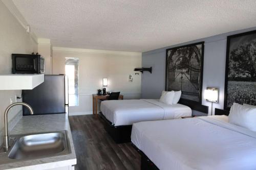 a hotel room with two beds and a sink at Super 8 by Wyndham Austin South I-35 in Austin