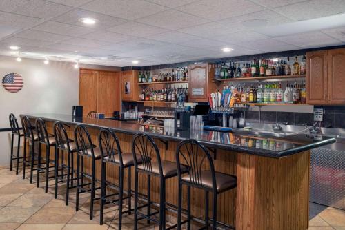 a bar with a row of black stools at AmericInn by Wyndham Aberdeen Event Center in Aberdeen