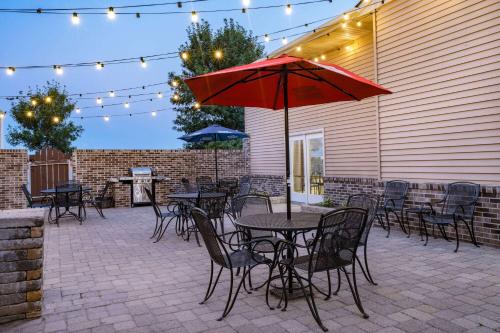 a patio with tables and chairs and a red umbrella at AmericInn by Wyndham Aberdeen Event Center in Aberdeen