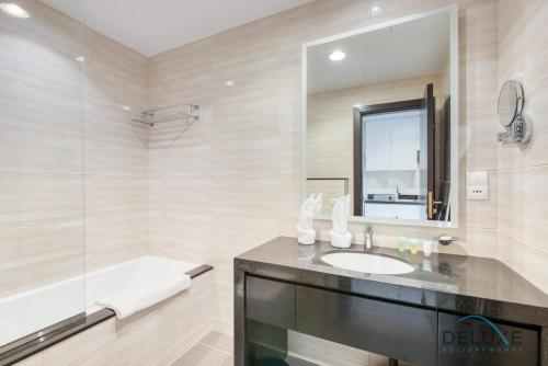 a bathroom with a sink and a mirror and a tub at Posh Studio at Celestia A Dubai South by Deluxe Holiday Homes in Dubai