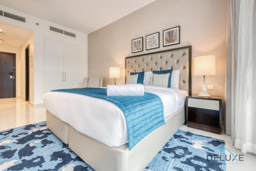 a bedroom with a large bed and a blue rug at Posh Studio at Celestia A Dubai South by Deluxe Holiday Homes in Dubai