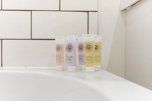 a row of three bottles of sunscreen on a shelf in a bathroom at Redhill town centre apartment by Livingo in Redhill